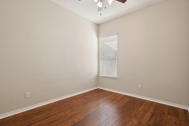 spare room featuring dark wood-style floors, a ceiling fan, and baseboards