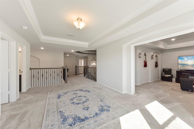 hallway with ornamental molding, a raised ceiling, and visible vents