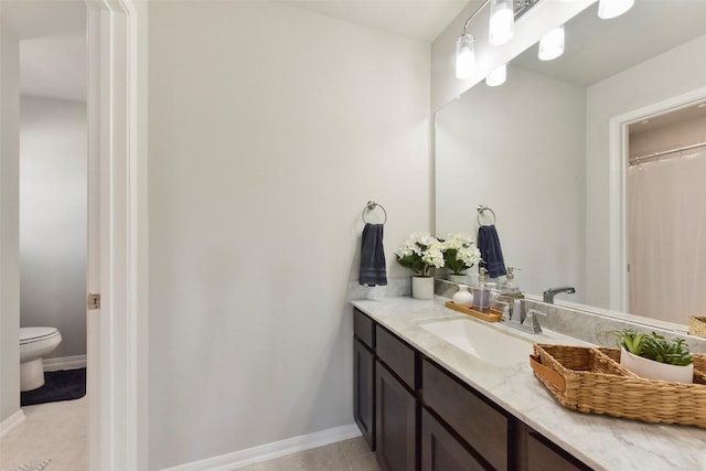 bathroom featuring baseboards, vanity, toilet, and tile patterned floors