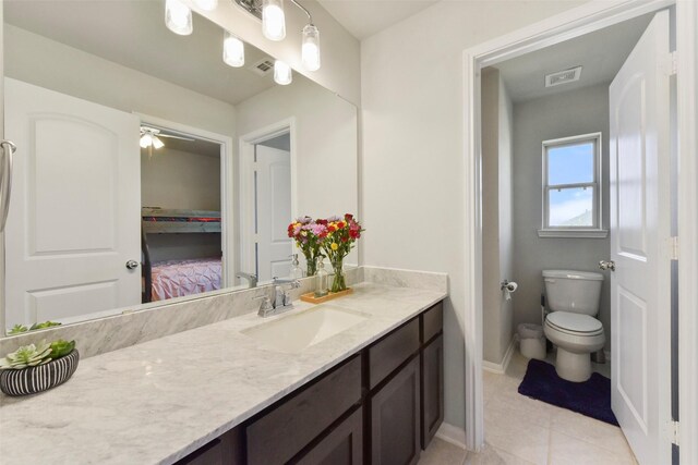 bathroom featuring visible vents, toilet, vanity, baseboards, and tile patterned floors