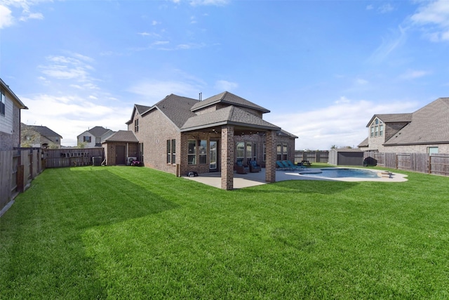 back of house with a fenced backyard, a lawn, a patio, and brick siding