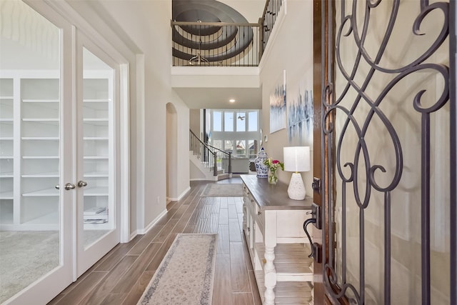 entryway with wood tiled floor, arched walkways, baseboards, and stairs