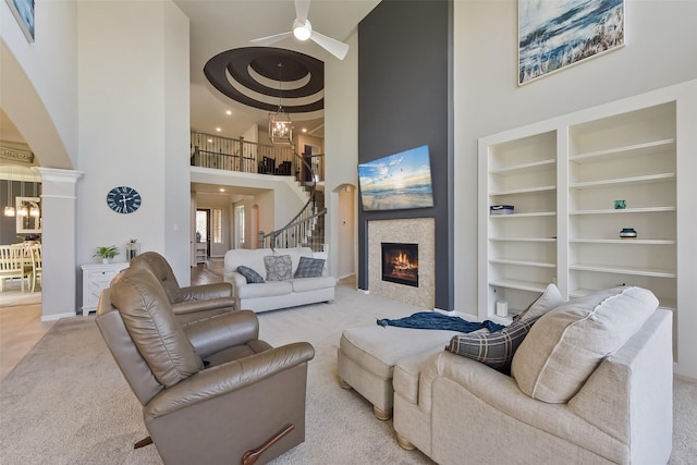 living area with built in features, a fireplace, a high ceiling, carpet flooring, and stairs