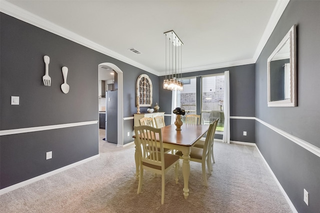 carpeted dining room featuring baseboards, visible vents, arched walkways, and ornamental molding