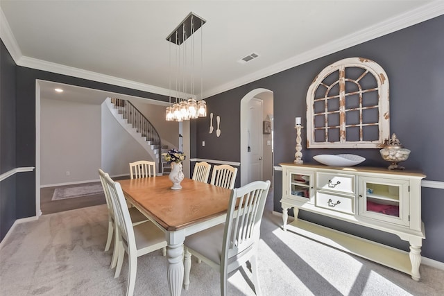 carpeted dining area featuring baseboards, visible vents, arched walkways, stairway, and ornamental molding