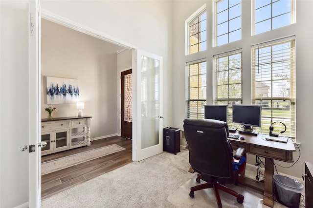 office space featuring french doors, a high ceiling, baseboards, and wood finished floors