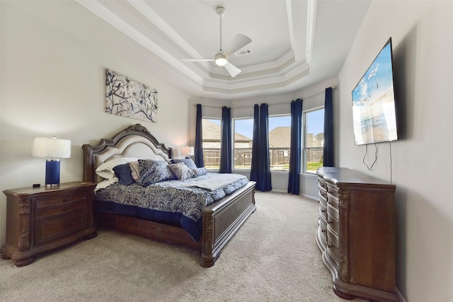 bedroom with carpet, visible vents, a tray ceiling, and a ceiling fan