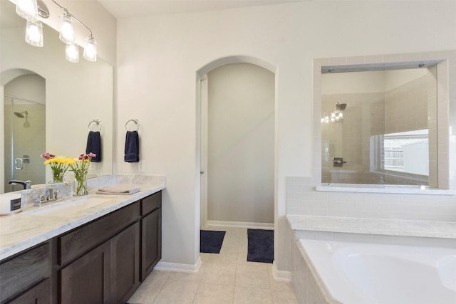 bathroom with a tile shower, vanity, tile patterned flooring, baseboards, and a bath