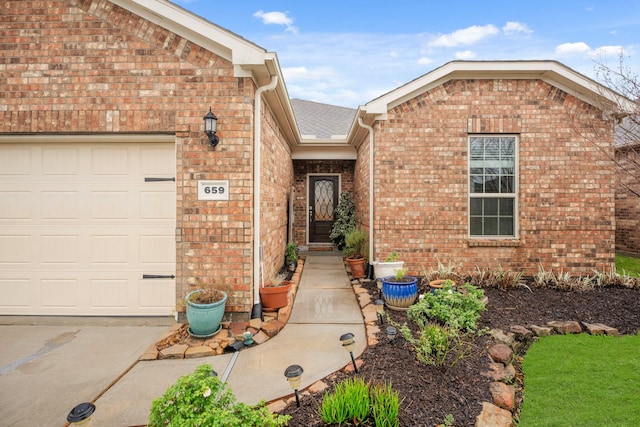 entrance to property with a garage and brick siding