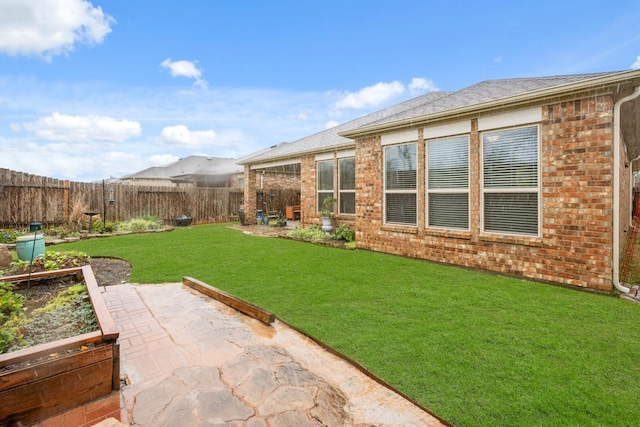 view of yard featuring a patio, a fenced backyard, and a garden