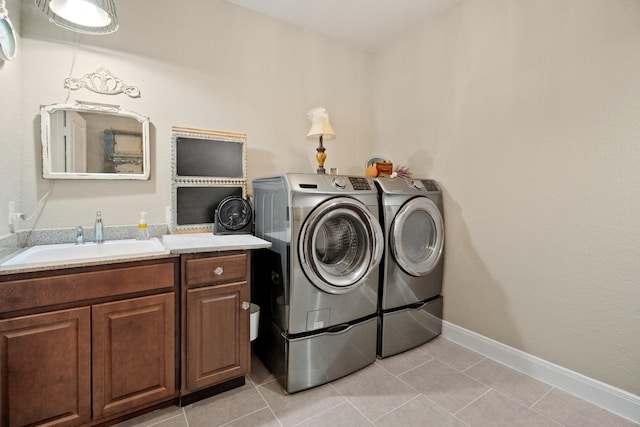 laundry area with light tile patterned floors, cabinet space, baseboards, washing machine and clothes dryer, and a sink