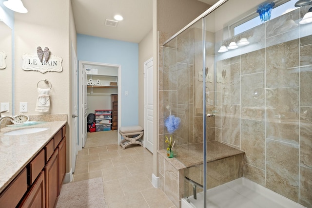 bathroom featuring a stall shower, visible vents, tile patterned floors, a walk in closet, and vanity