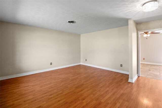 spare room featuring light wood-type flooring, visible vents, ceiling fan, and baseboards