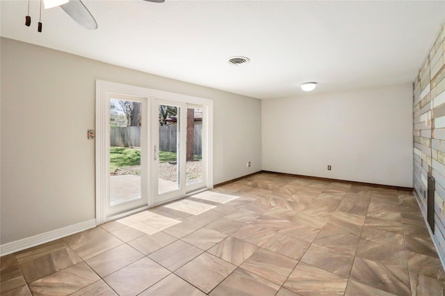 empty room featuring a ceiling fan, visible vents, and baseboards