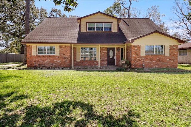 view of front of house featuring brick siding, fence, and a front lawn