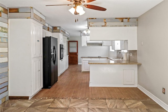 kitchen with white cabinets, a peninsula, under cabinet range hood, black appliances, and a sink