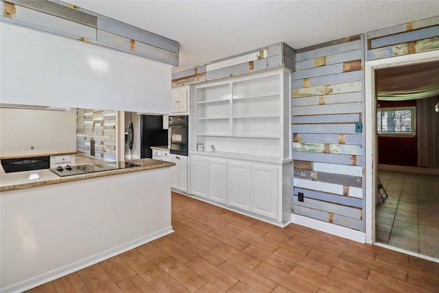 kitchen featuring extractor fan, light wood-style flooring, open shelves, white cabinetry, and black appliances