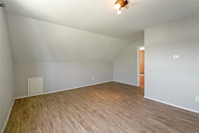 additional living space featuring baseboards, vaulted ceiling, and wood finished floors