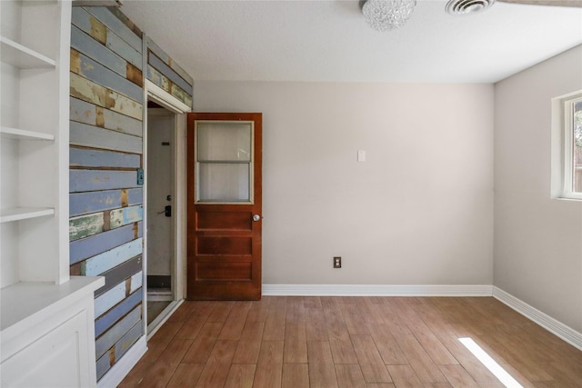 interior space with built in shelves, visible vents, baseboards, and wood finished floors