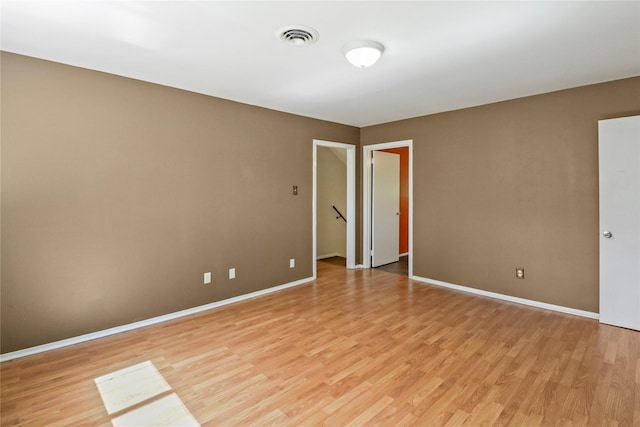 unfurnished room featuring light wood finished floors, baseboards, and visible vents