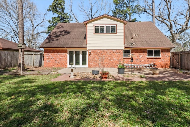 back of house with french doors, brick siding, a patio, a lawn, and a fenced backyard