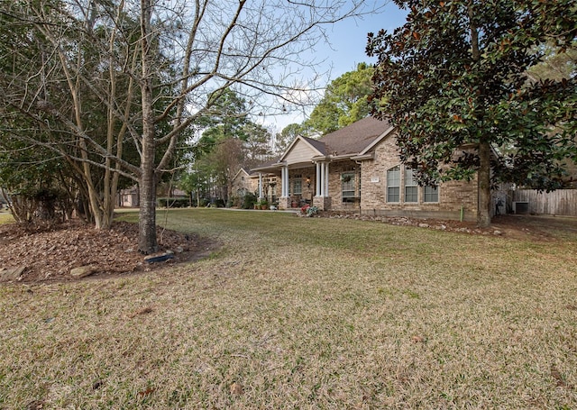 view of front of home featuring brick siding, fence, and a front lawn