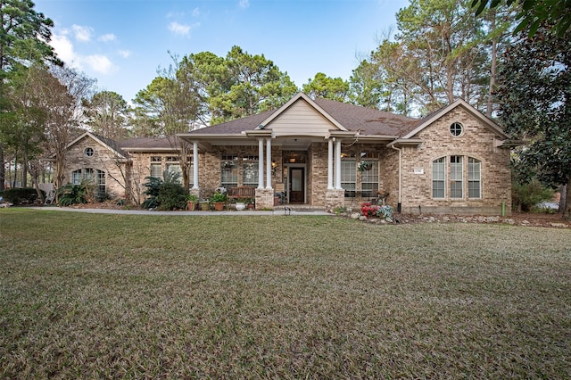 view of front of house featuring a shingled roof, brick siding, a porch, and a front lawn