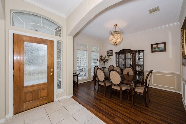 entrance foyer featuring visible vents, arched walkways, crown molding, light wood-style floors, and a notable chandelier