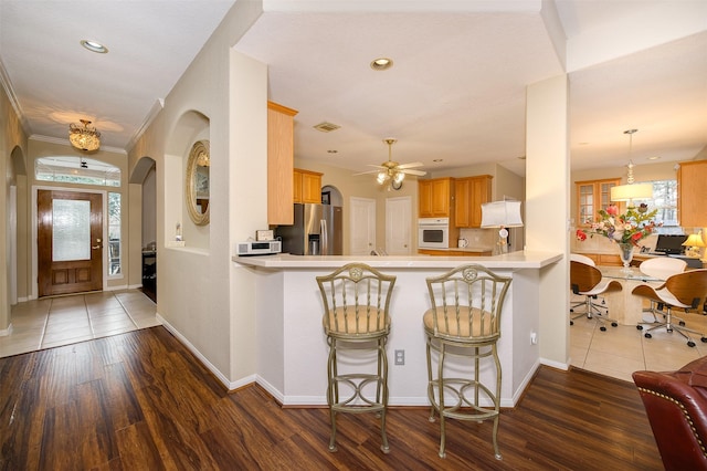 kitchen with stainless steel refrigerator with ice dispenser, recessed lighting, light countertops, wood finished floors, and oven