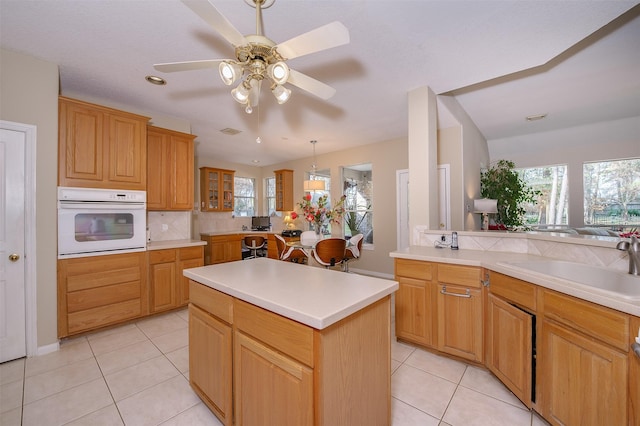 kitchen featuring white oven, light countertops, a sink, and light tile patterned floors