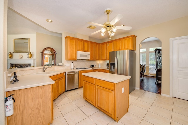 kitchen with light tile patterned floors, visible vents, arched walkways, stainless steel appliances, and a sink