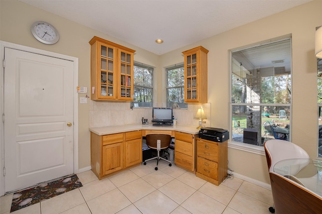 office area featuring baseboards, built in desk, and light tile patterned flooring