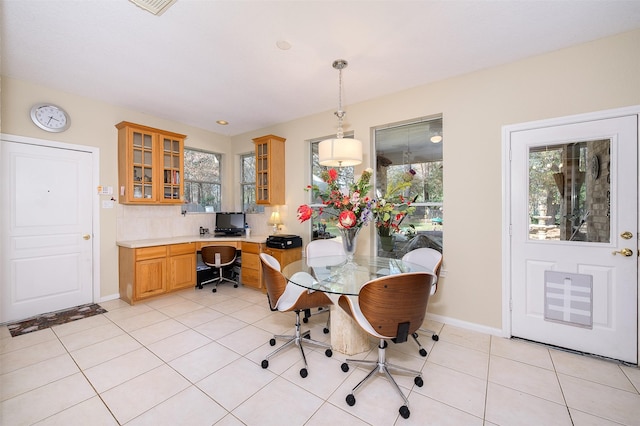 dining space with built in desk, baseboards, and light tile patterned floors