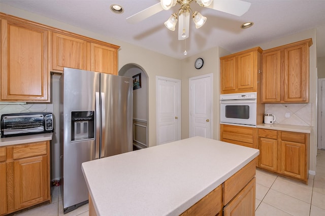 kitchen featuring light tile patterned floors, stainless steel fridge, a toaster, white oven, and light countertops