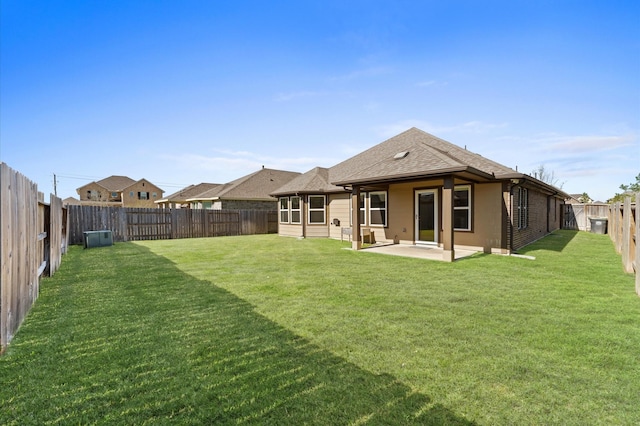 rear view of house featuring a patio area, a fenced backyard, a lawn, and roof with shingles