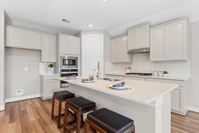 kitchen featuring light countertops, appliances with stainless steel finishes, a sink, and under cabinet range hood