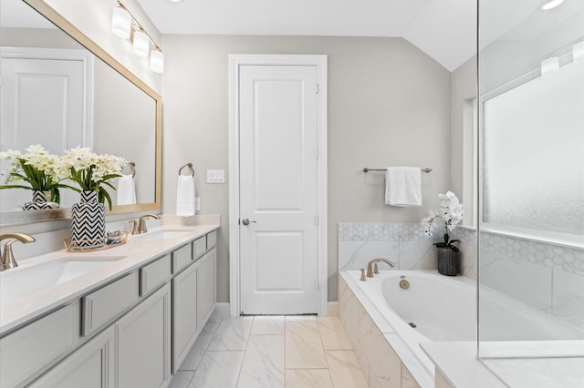 bathroom with a garden tub, double vanity, vaulted ceiling, and a sink