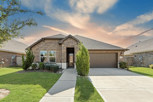 view of front of house featuring brick siding, a lawn, an attached garage, and fence