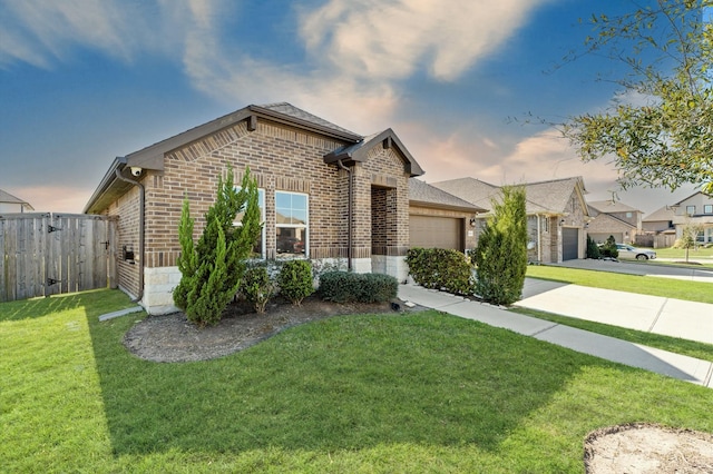 view of front of house featuring driveway, an attached garage, fence, a yard, and brick siding