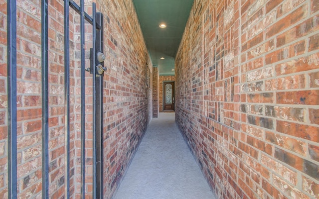 hallway featuring carpet, brick wall, and recessed lighting