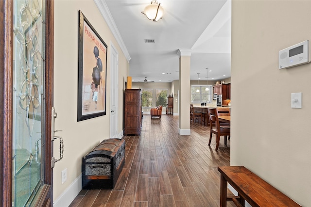 foyer entrance with dark wood-style flooring, decorative columns, visible vents, ornamental molding, and baseboards