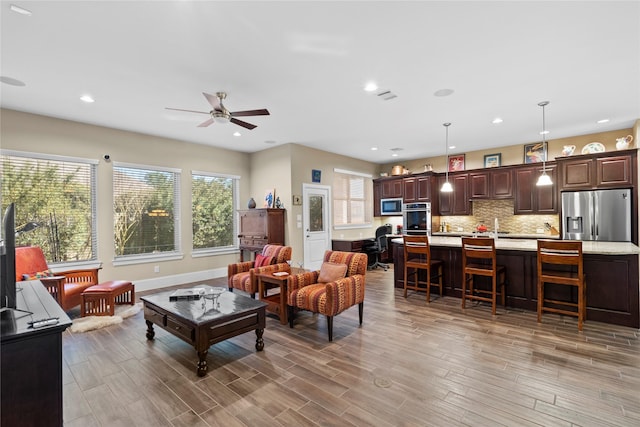 living area with light wood finished floors, ceiling fan, baseboards, and recessed lighting