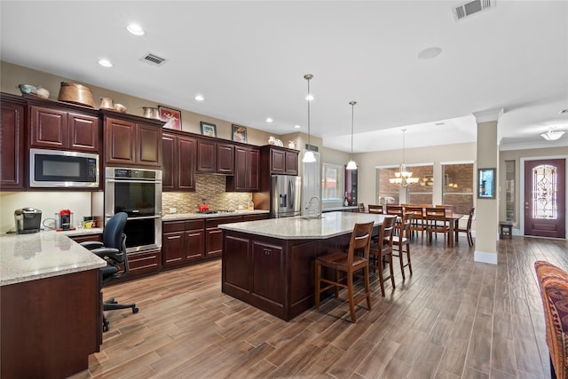 kitchen with stainless steel appliances, tasteful backsplash, visible vents, and wood finished floors