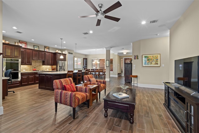 living room with ornate columns, wood tiled floor, and visible vents