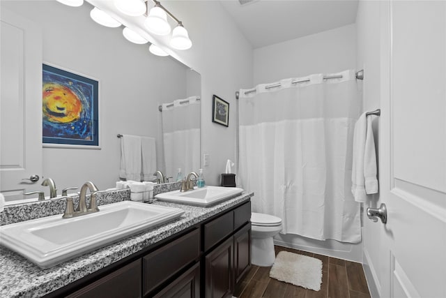 full bath featuring toilet, wood tiled floor, double vanity, and a sink