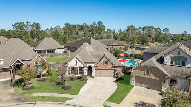 french country inspired facade with stone siding, a residential view, a front lawn, and concrete driveway