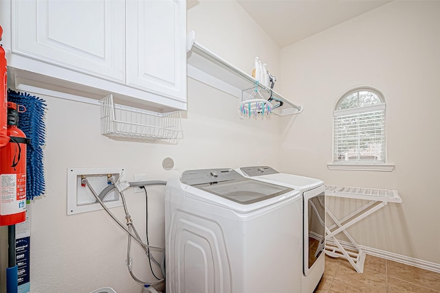 laundry room with cabinet space, light tile patterned floors, baseboards, and washer and clothes dryer