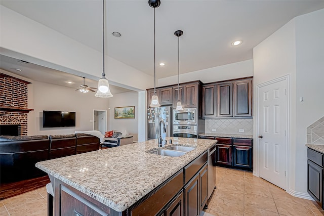 kitchen with decorative light fixtures, decorative backsplash, appliances with stainless steel finishes, open floor plan, and dark brown cabinets