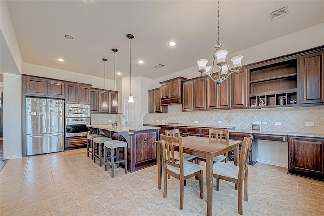 kitchen with stainless steel appliances, tasteful backsplash, visible vents, and light stone countertops