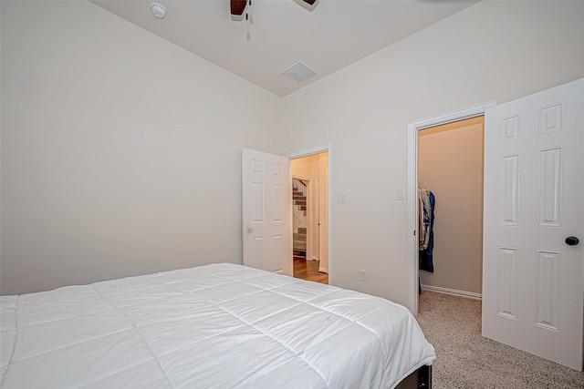 carpeted bedroom with a spacious closet, a closet, visible vents, and a ceiling fan